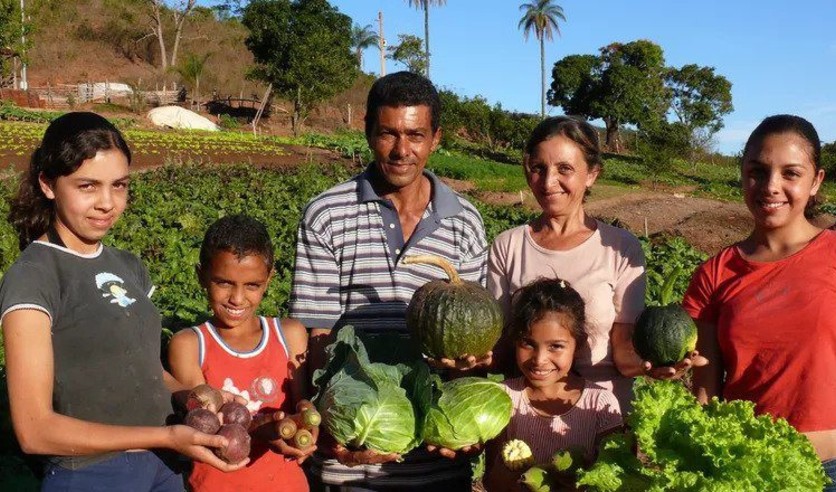 Family of agricultures in the countryside holding their produce